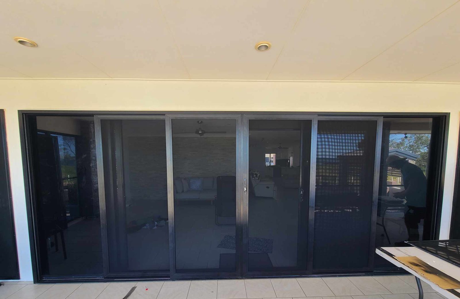Long side of an elevated new home at sunset, its upper level closed in with dark mesh screens