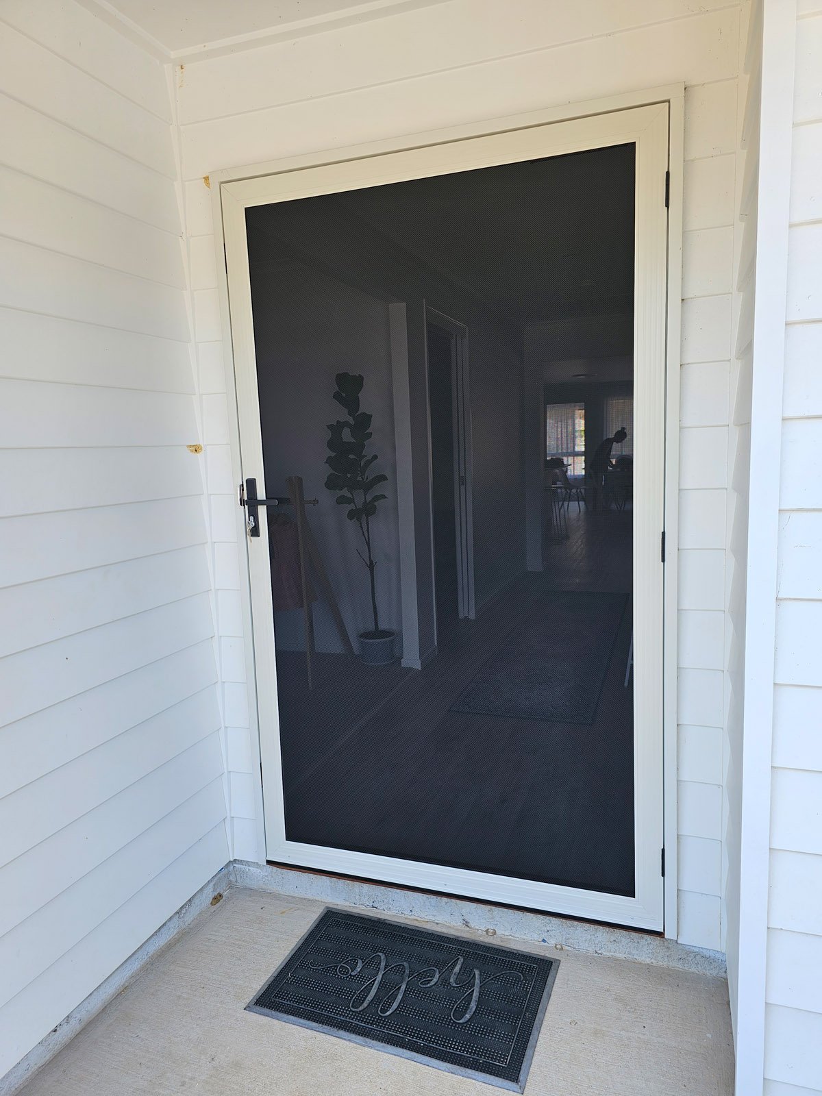 White hinged security door with clear see-through mesh at a front entry
