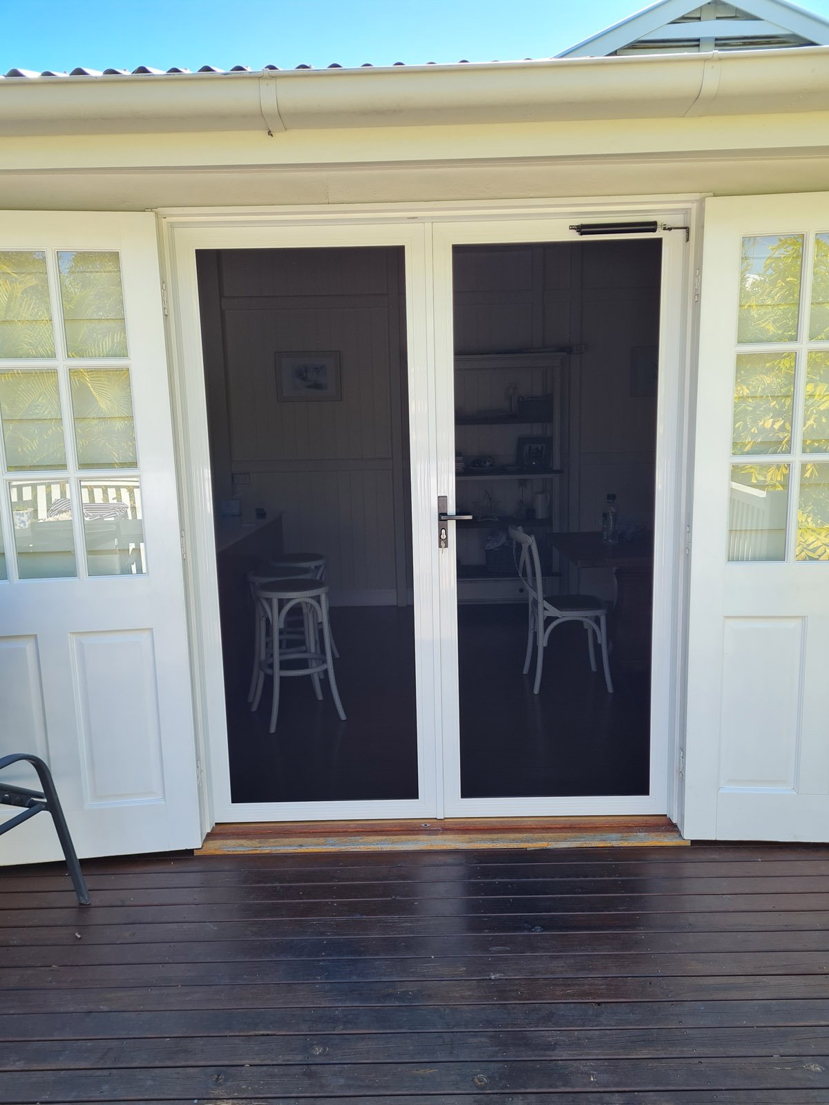 Double French security doors with white frames opening onto a timber deck
