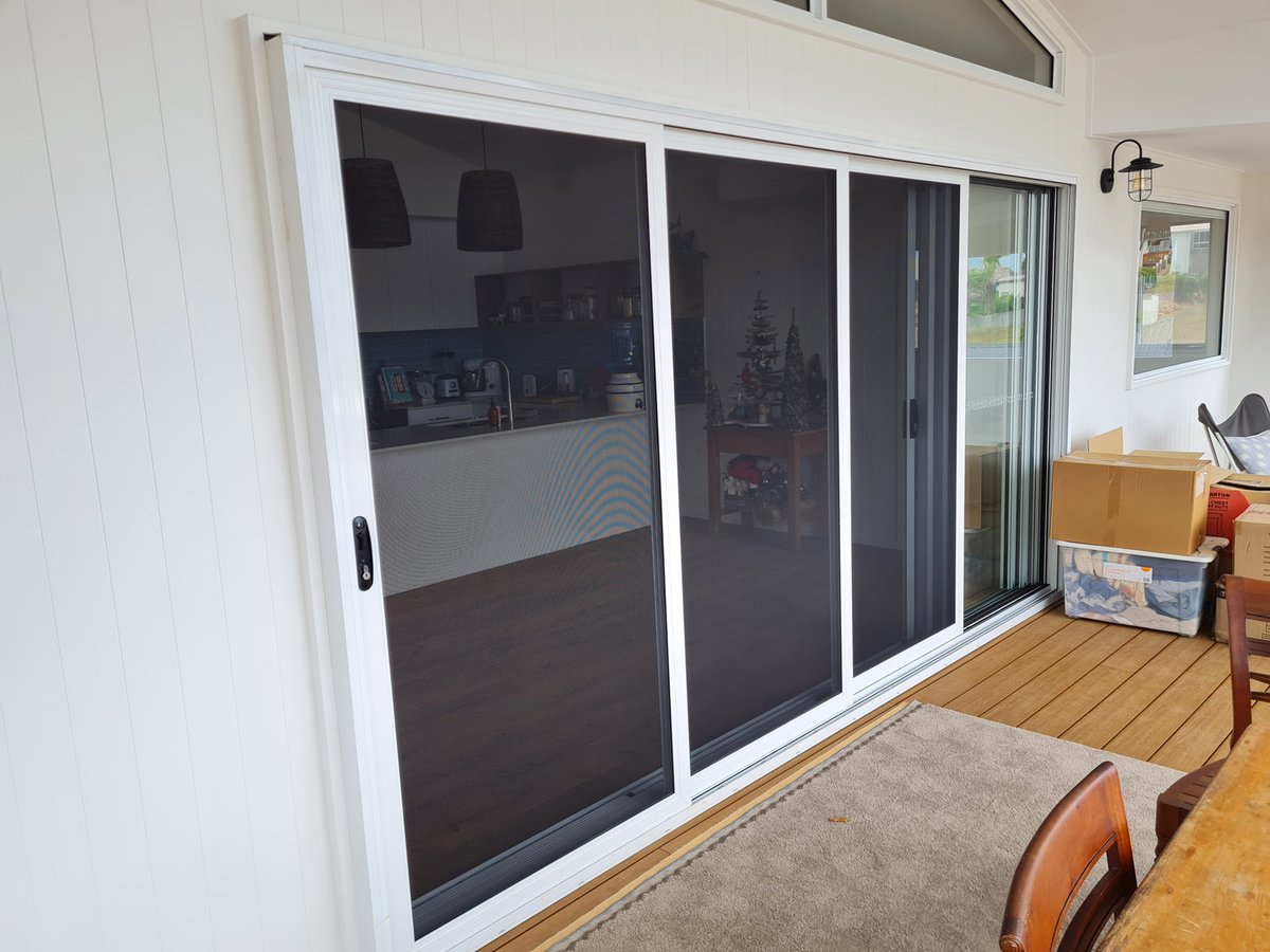 Two panel sliding security door opening onto a timber deck on a white weatherboard home
