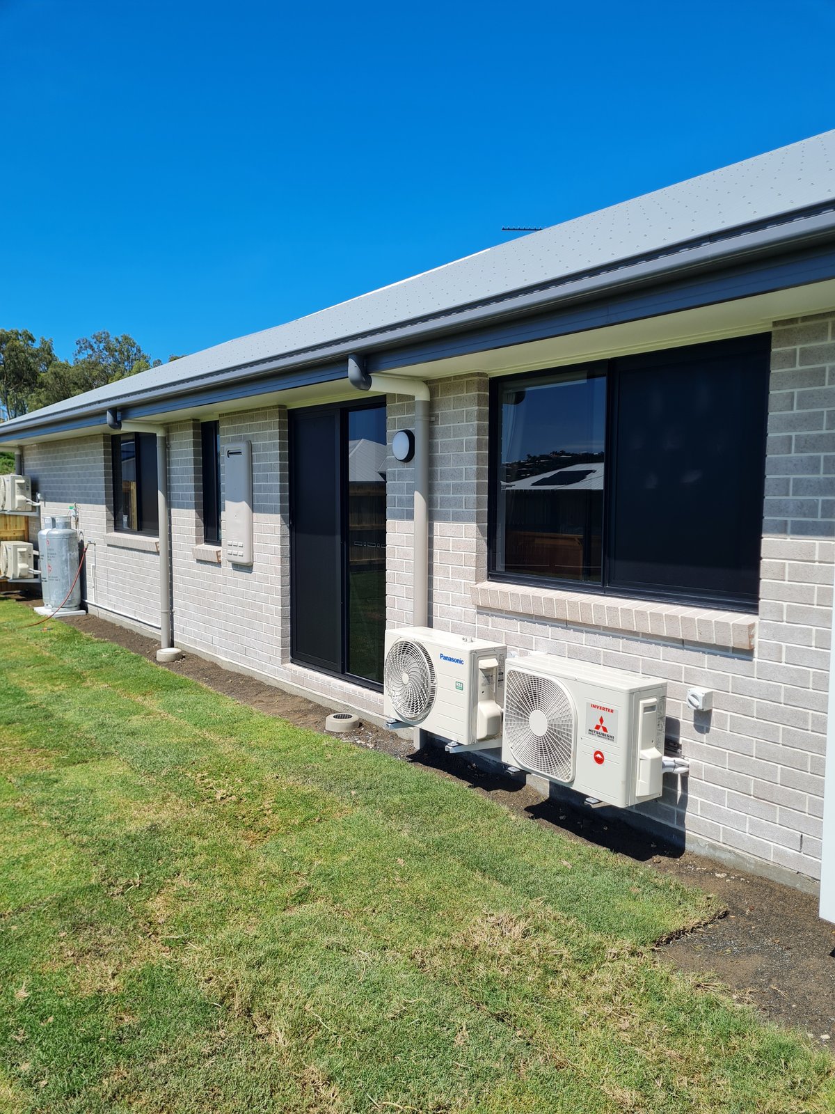New brick home with dark screens fitted to a window and the sliding door